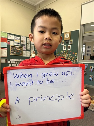 Child holding a sign which says - when I grow up I want to be a principle