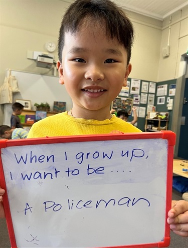 Child holding a sign which says - when I grow up I want to be a policeman
