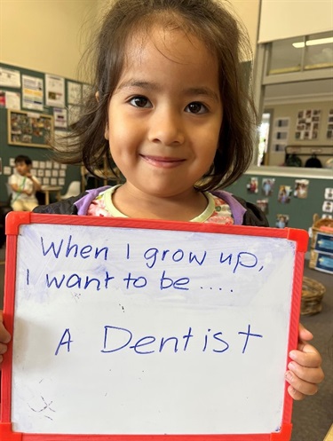 Child holding a sign which says - when I grow up I want to be a dentist