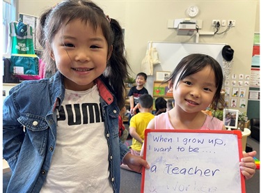 Child holding a sign which says - when I grow up I want to be a teacher