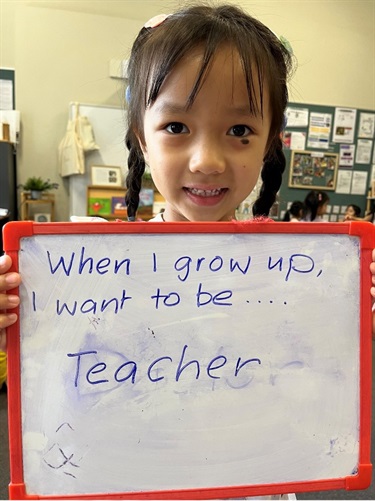 Child holding a sign which says - when I grow up I want to be a teacher