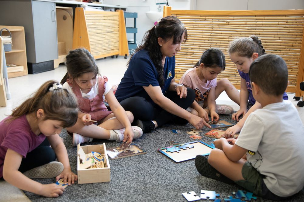 Carer helping children build puzzles