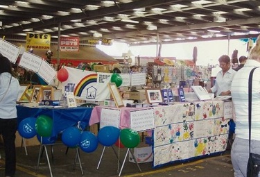 Family Day Care stall holder table, decorated with colourful paintings and balloons, at the Fairfield City Markets