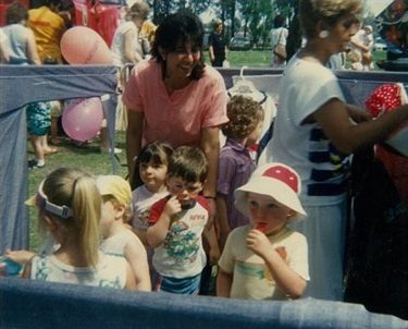 Adults and young children smiling and playing on Picnic Day in celebration of Children's Week, at the Council Chambers' Grounds