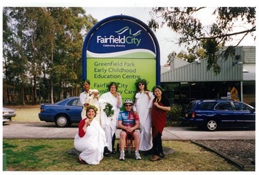 Women dressed in togas and olive wreaths smiling and posing with athlete for the 2000 Olympic Games