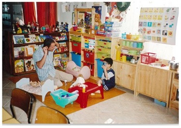 Man playing with young child during play group service at carer's home