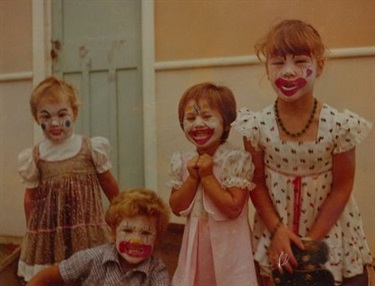 Group of young children smiling and posing with clown face paint