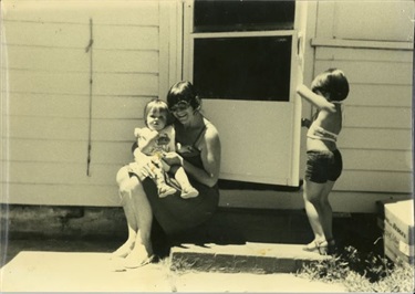 Educator smiling and posing with young children in 1976