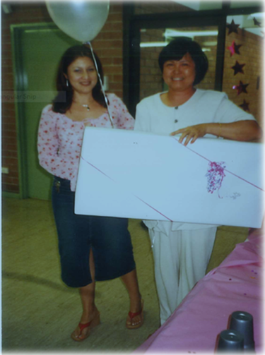 Two women smiling and posing, while holding large prize