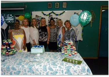 amily Day Care educators smiling and posing behind table for 40 Years Celebration