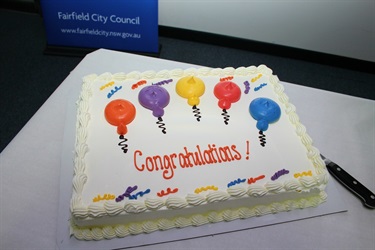 A white cake with colourful icing decorations, saying Congratulations!