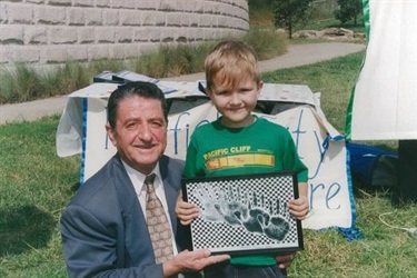 Major Anwar smiling and posing with young boy, holding framed image