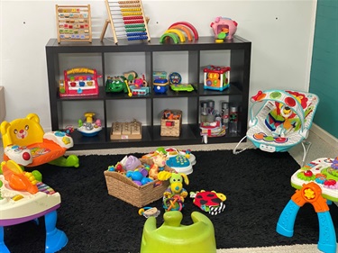 An assortment of colourful interactive toys on a shelf and in boxes at the children's activity corner