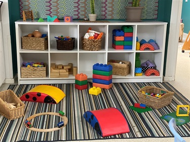An assortment of different coloured and types of building blocks, wooden train tracks and foam bridges at the children's activity corner