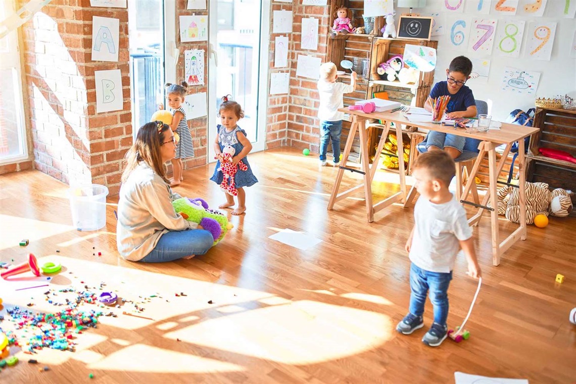 Woman sitting on the floor with 5 children playing with toys